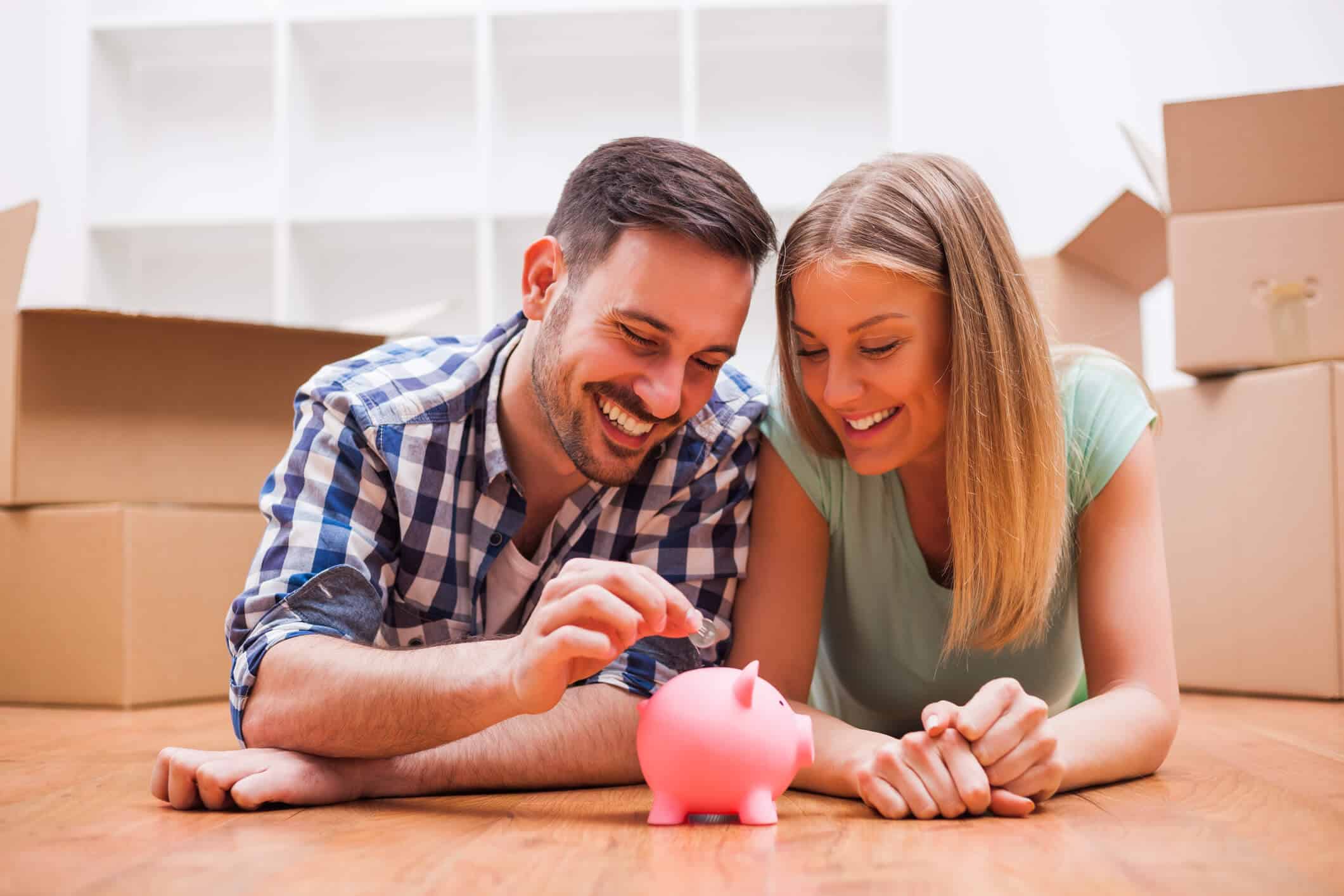 two people lying on a floor putting coins in a piggy bank
