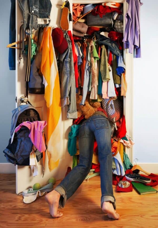 view of a person from behind, with their head inside a overstuffed clothes closet