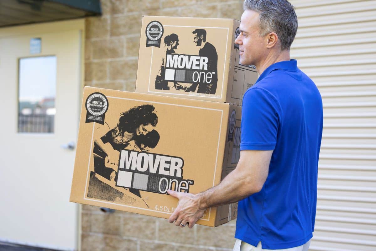 man in blue shirt carrying two moving boxes