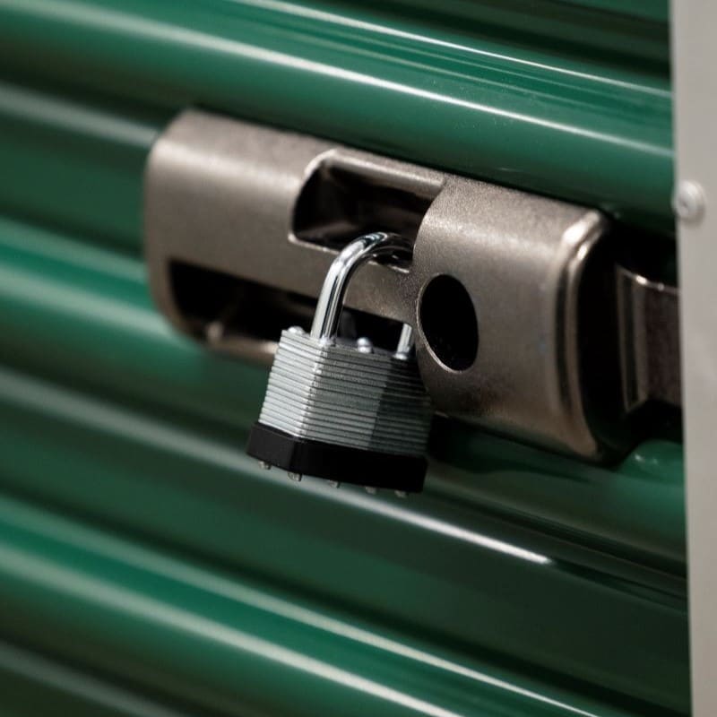 green storage unit door secured by a padlock