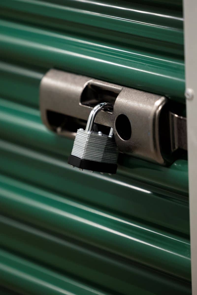 green storage unit door secured with a padlock