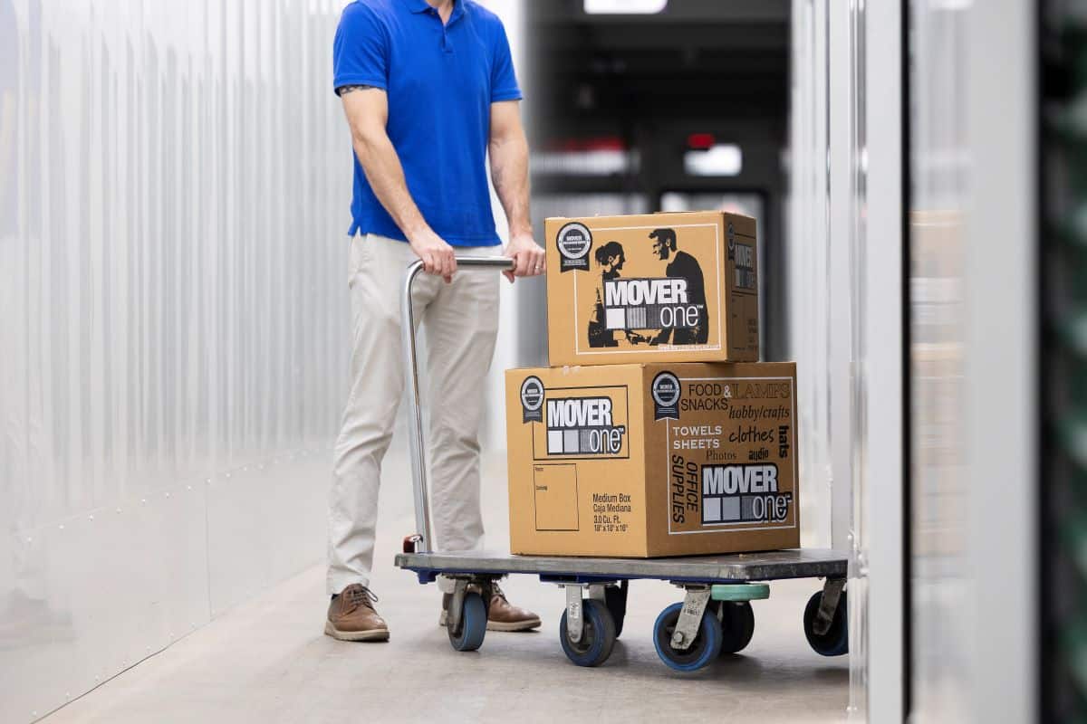 view of a person pushing a moving cart loaded with boxes into a storage unit