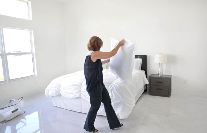 person putting a pillow onto a bed