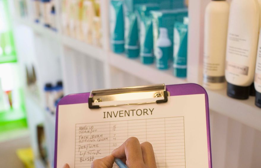 person holding a clipboard with a sheet for inventory management with shelves of product in the background