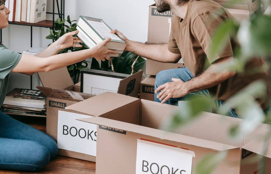 two people putting books in boxes for storage